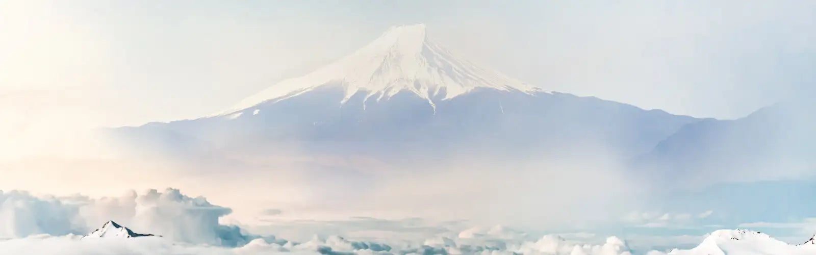 Snow-capped mount fuji rises majestically against a soft, hazy sky.