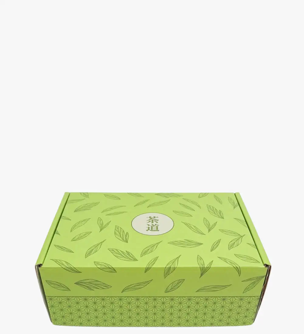 Lime green cardboard box adorned with a repeating leaf pattern and featuring the chinese characters ’茶道’ in a central circular emblem.