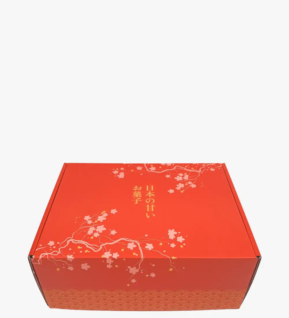Red cardboard gift box with delicate white cherry blossom and gold leaf patterns, featuring japanese text along the side.